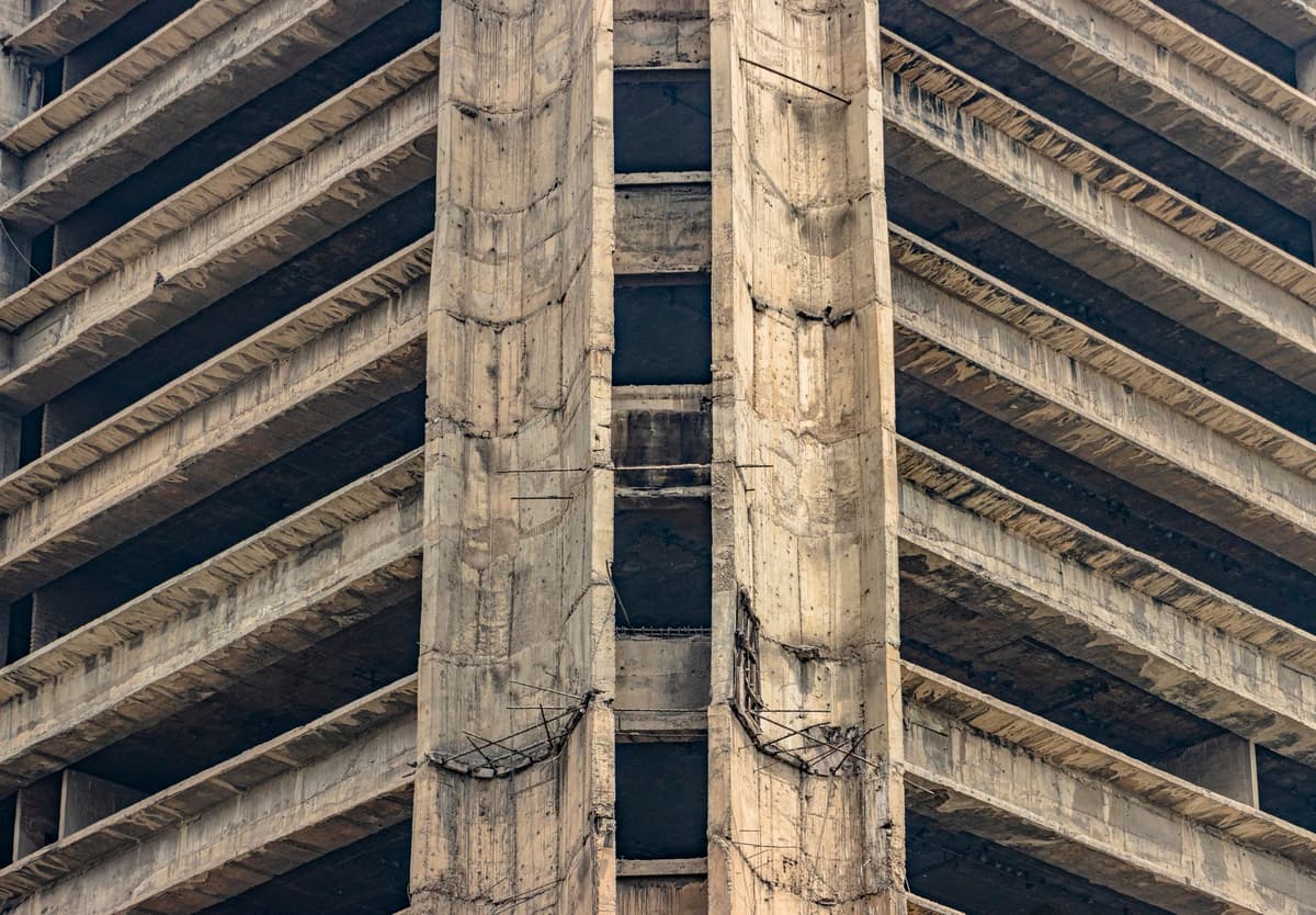 a brutalist concrete parking garage structure viewed from below against a gray sky