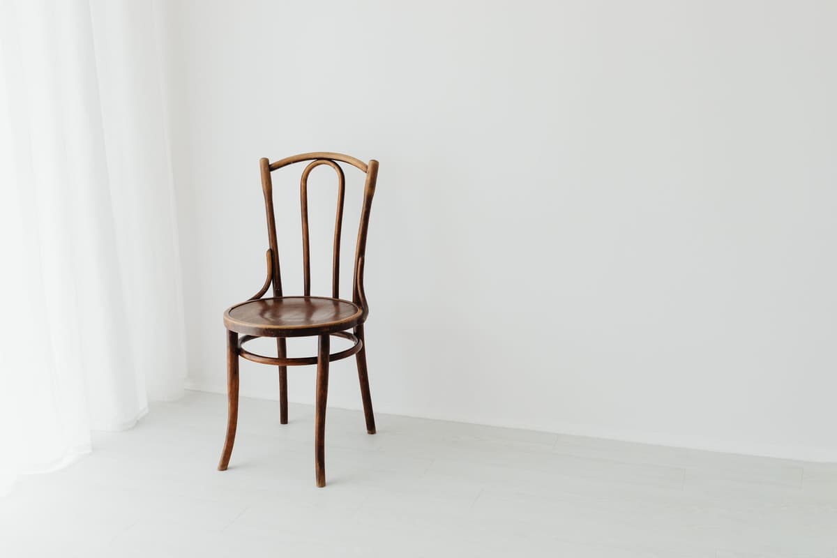 a single gray chair in an empty white room