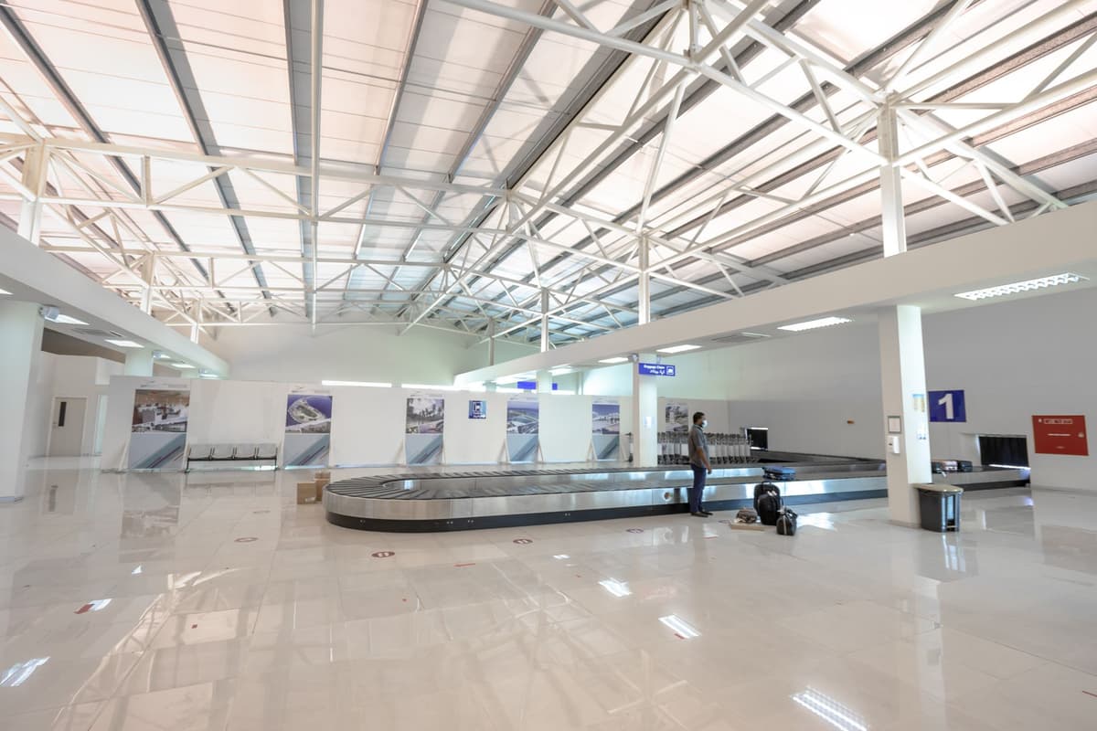 a single suitcase sitting on a massive empty airport baggage carousel
