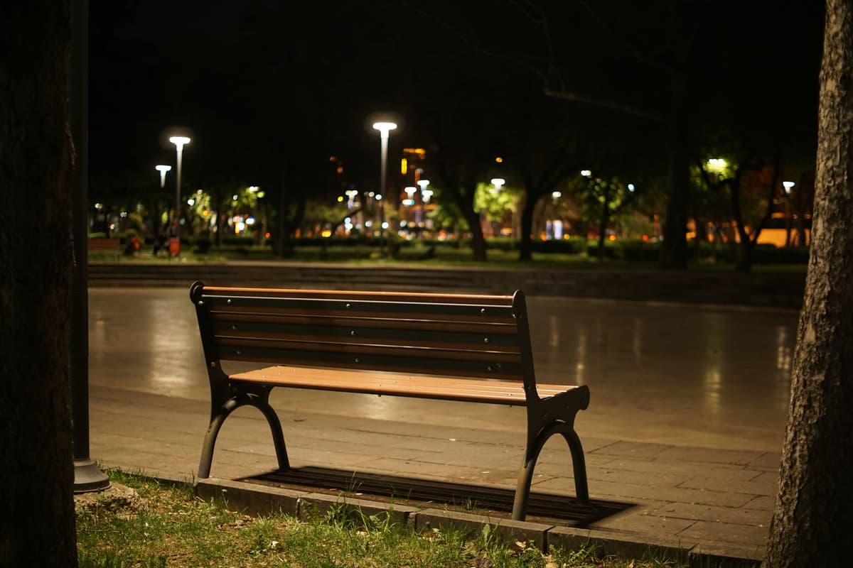 person staring blankly at an empty park bench