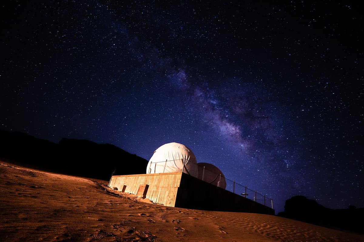 a massive white radio telescope dish pointed at a dark night sky filled with faint stars