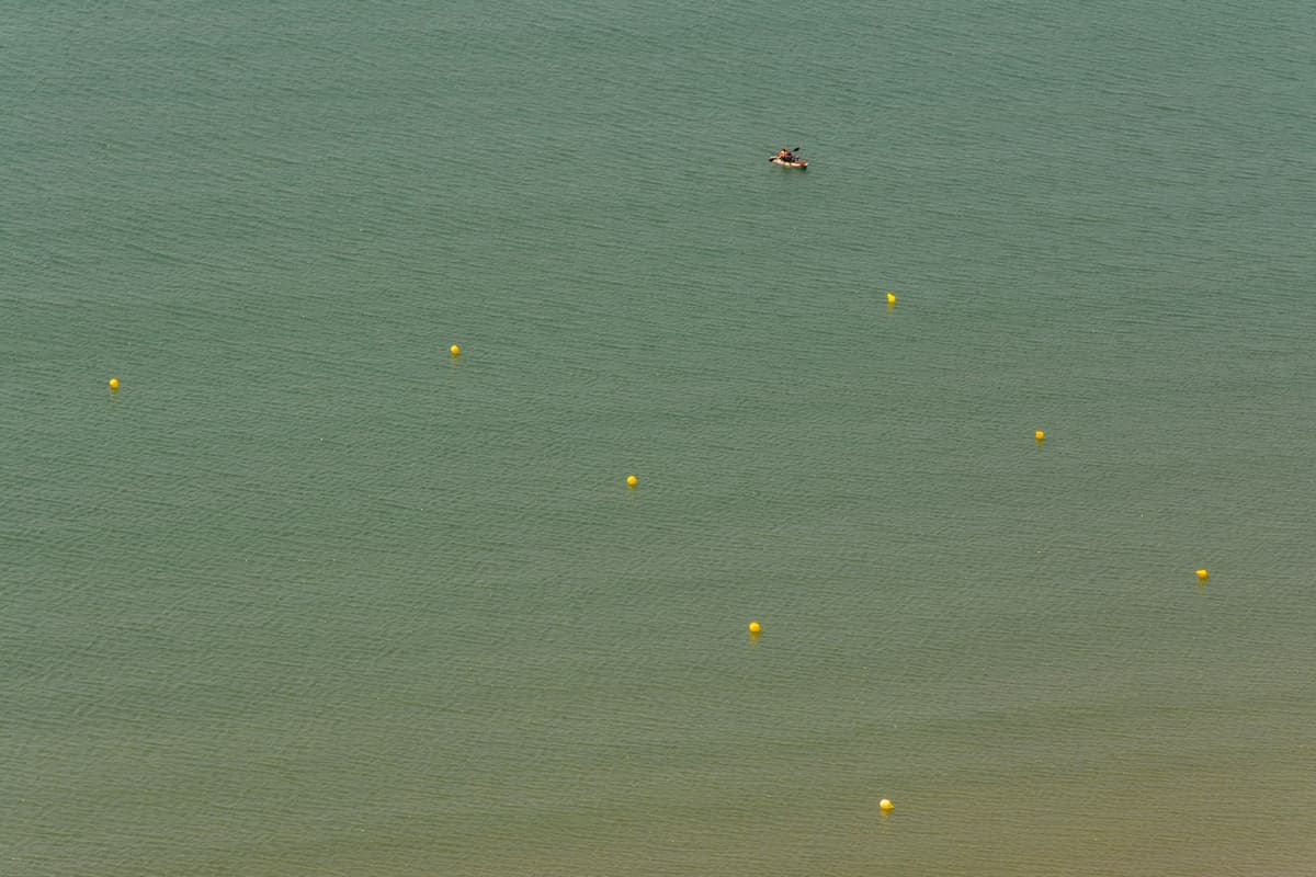 a single yellow rotary phone floating on calm blue ocean water