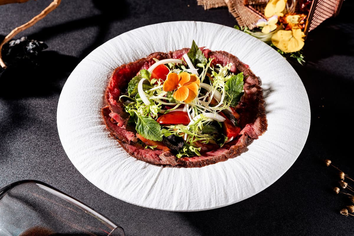 a single raw cow heart served on a minimalist white marble plate