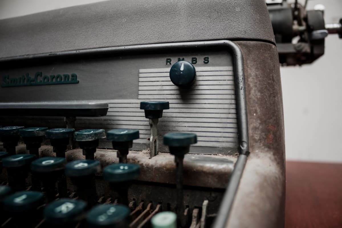 a dusty typewriter sitting next to an expensive tablet