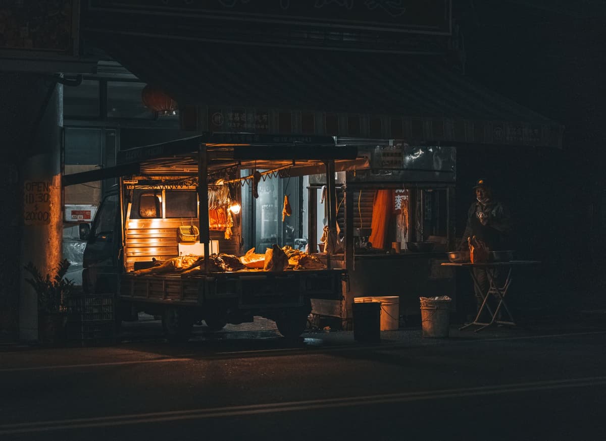 a neon-lit ramen stall in a rainy alleyway