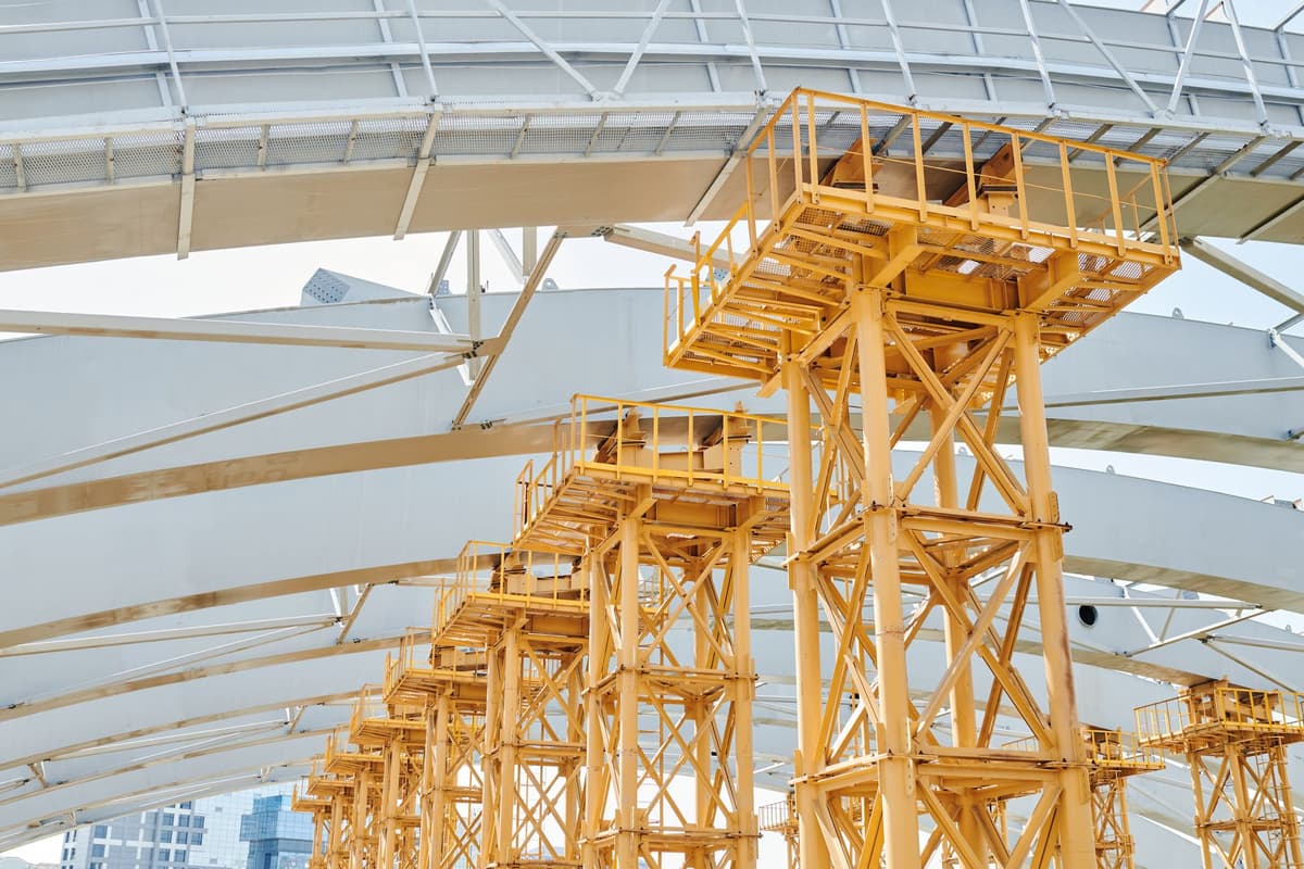a massive steel sphere hanging from yellow industrial cables inside a high-tech room