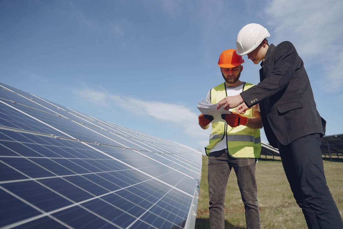 a farmer checking a tablet next to leafy greens under solar arrays