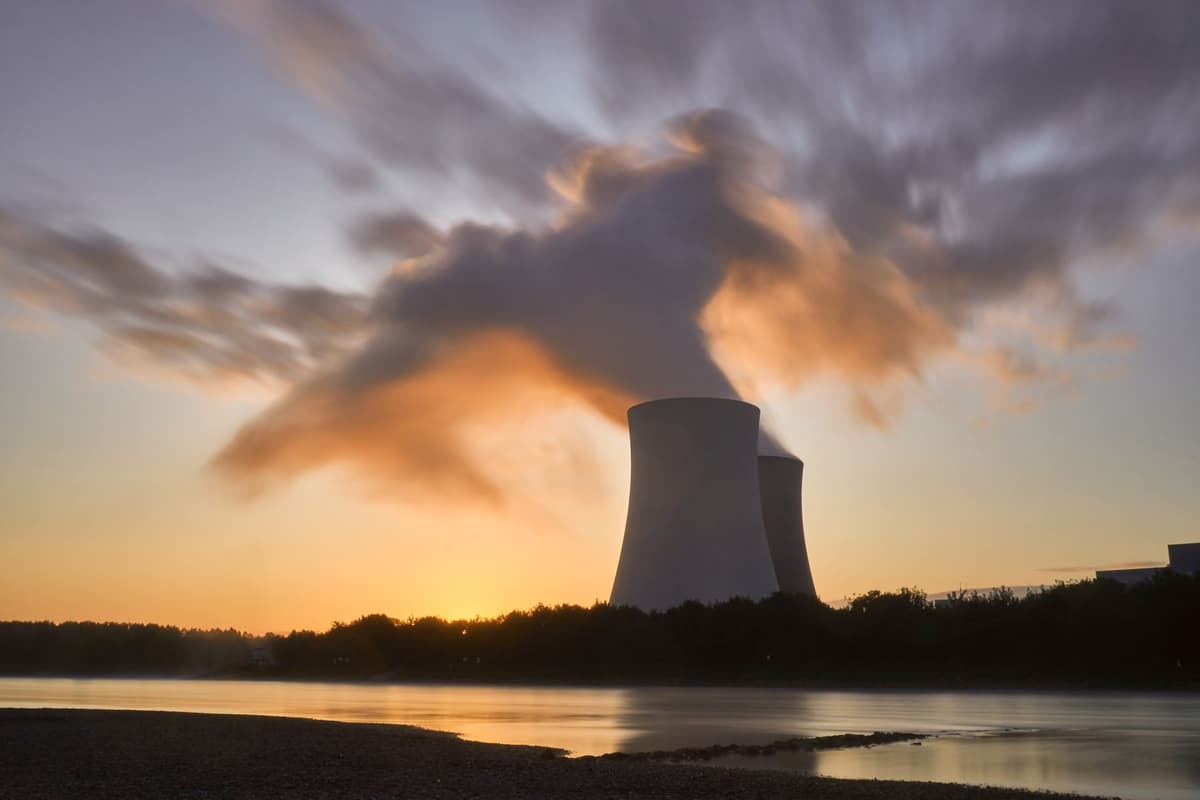 a massive cooling tower at a nuclear power plant against a clear sky