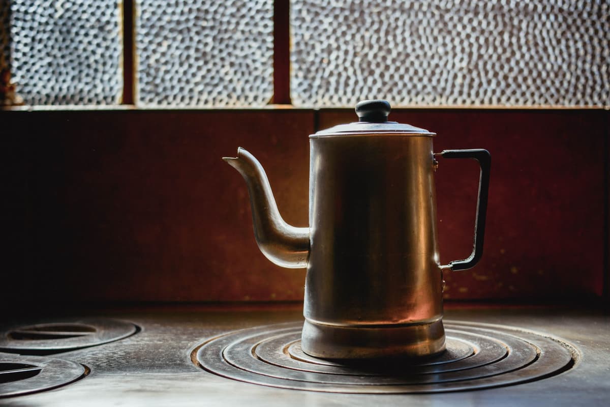 a rusted metal kettle whistling violently on a stove