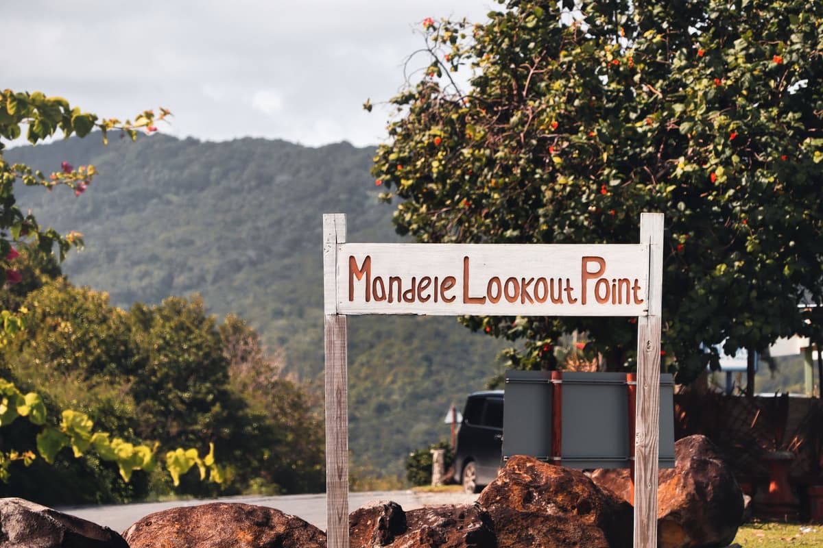 a hand-painted wooden sign pointing toward a distant snowy peak