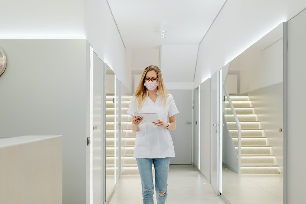 a nurse looking at a glowing tablet screen in a dark hallway