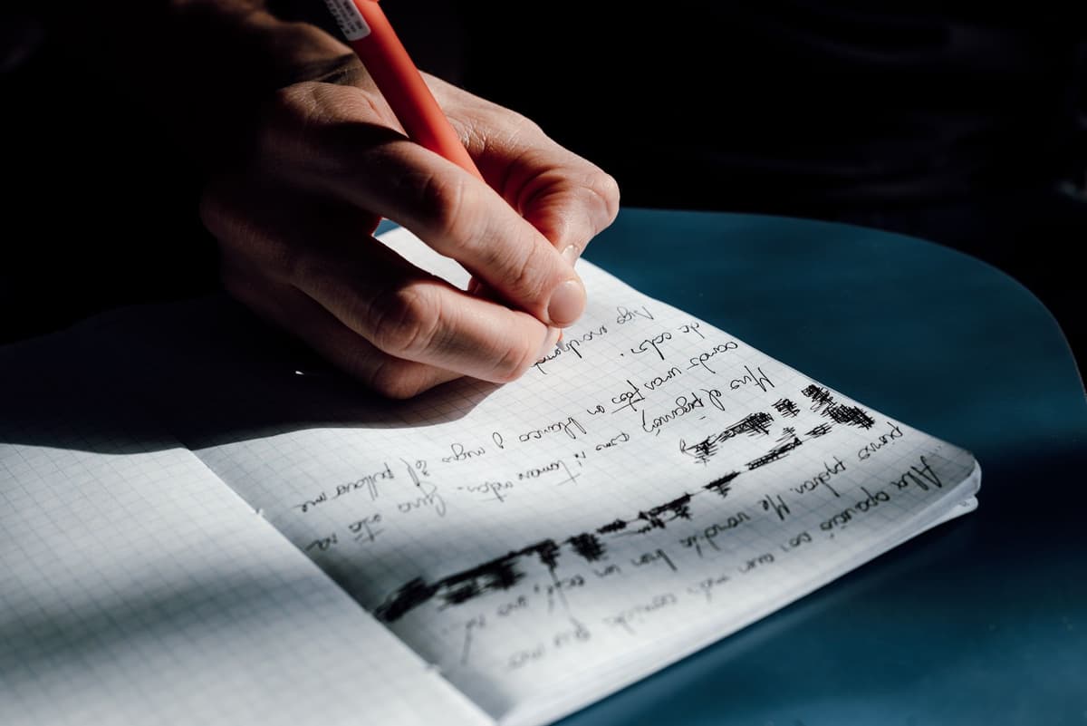 a hand pressing dark soil onto a thick paper page in a bound journal