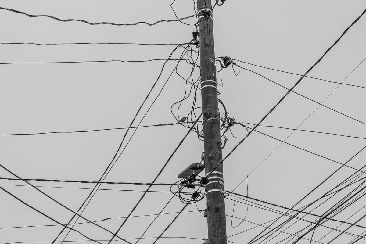 a tangled mess of black power cables on a wooden floor