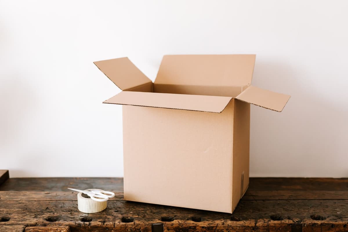 a cardboard shipping box with a simple black logo being taped shut