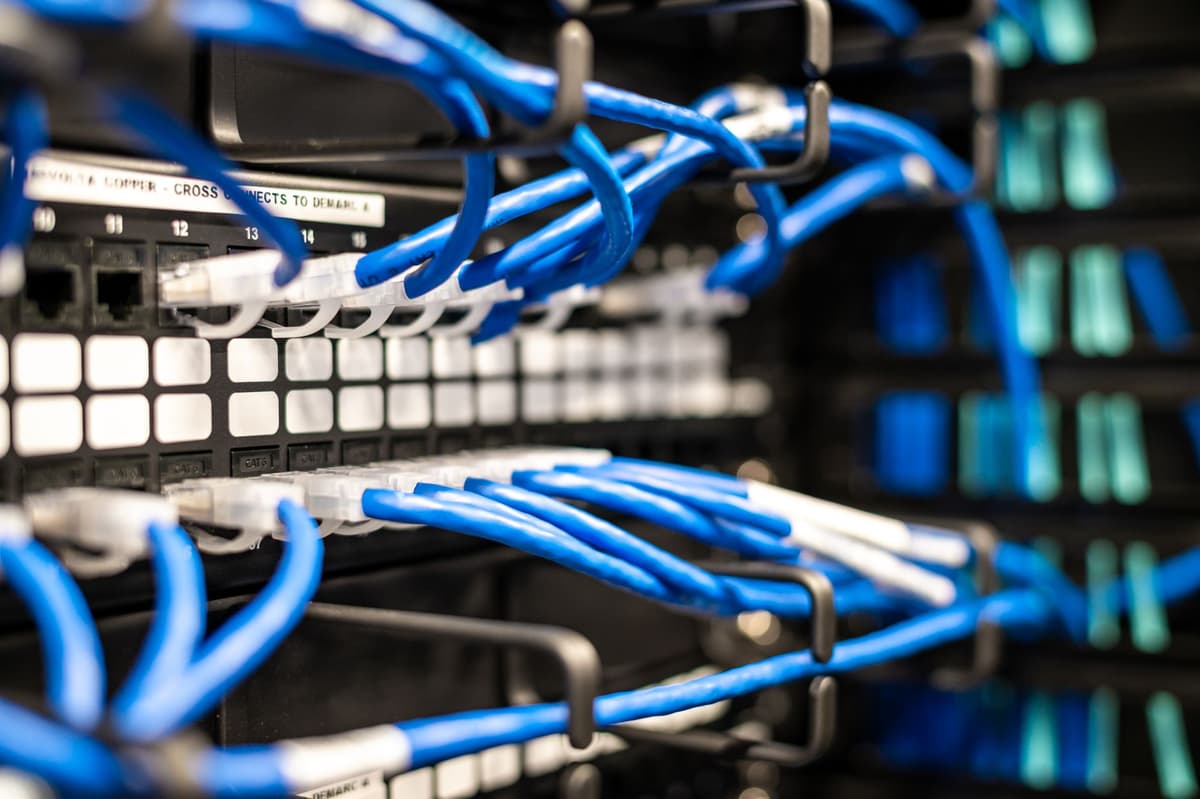 a close-up of dozens of silver patch cables plugged into a wooden synthesizer panel