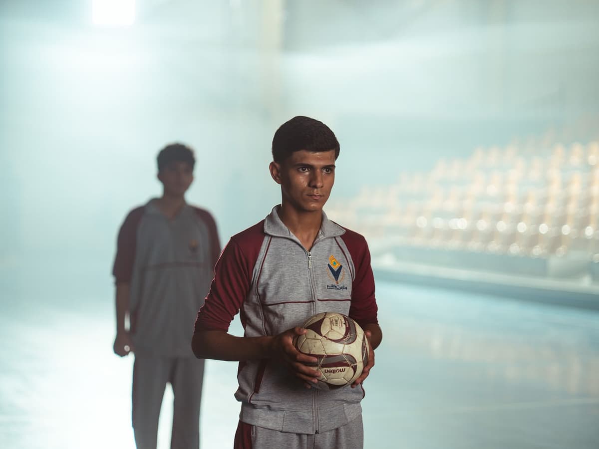 a man looking sadly at a petri dish while holding a soccer ball