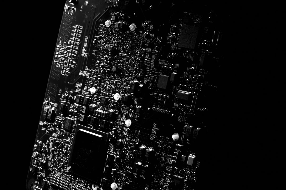 a high-contrast close-up of a soldering iron touching a microchip