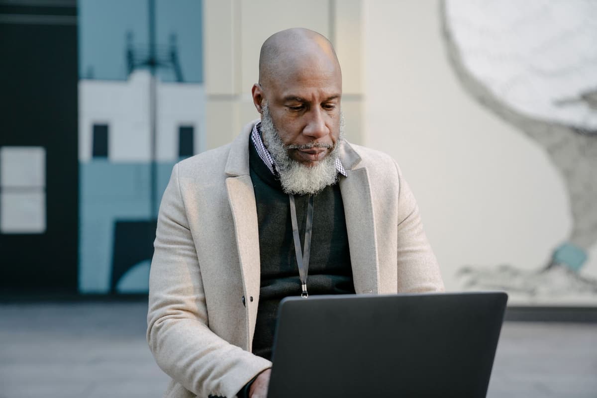a man looking intensely at a laptop while wearing a tinfoil hat made of ethernet cables