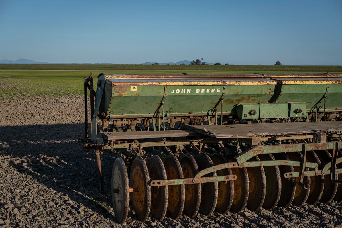 a lone rusted tractor in a vast cracked mud field