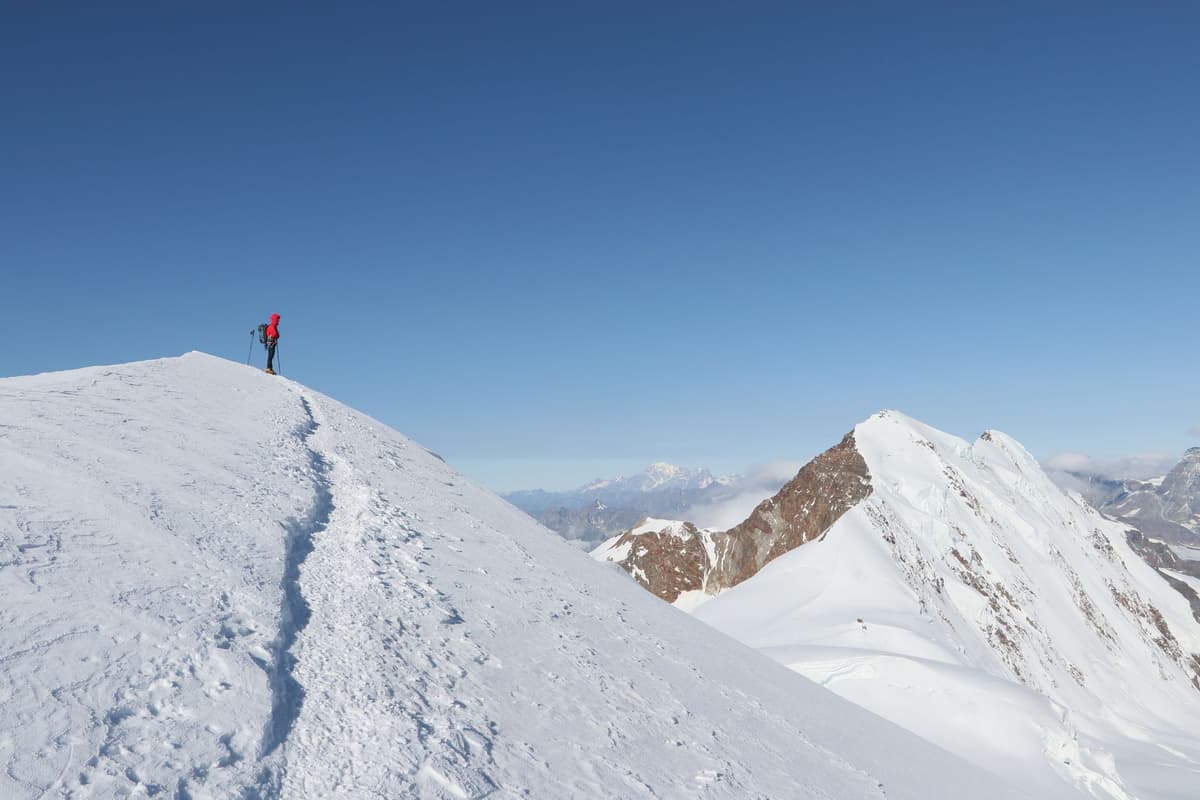 a line of climbers in bright parkas on a narrow ridge