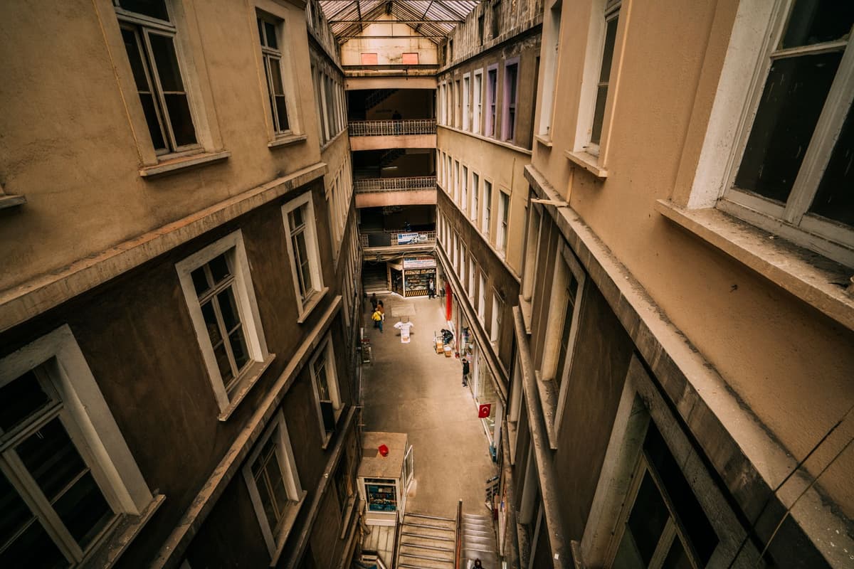 a narrow five-story building surrounded by massive department store walls